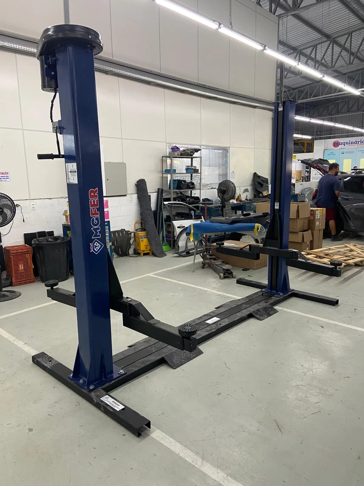 Elevador automotivo de duas colunas com motor, colunas e base à vista em oficina